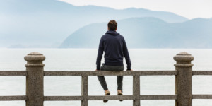 Hombre joven de espalda descansa frente a un lago